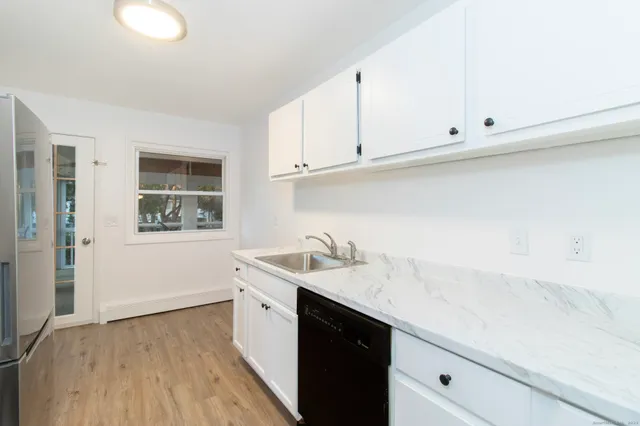 a kitchen with granite countertop white cabinets and a sink