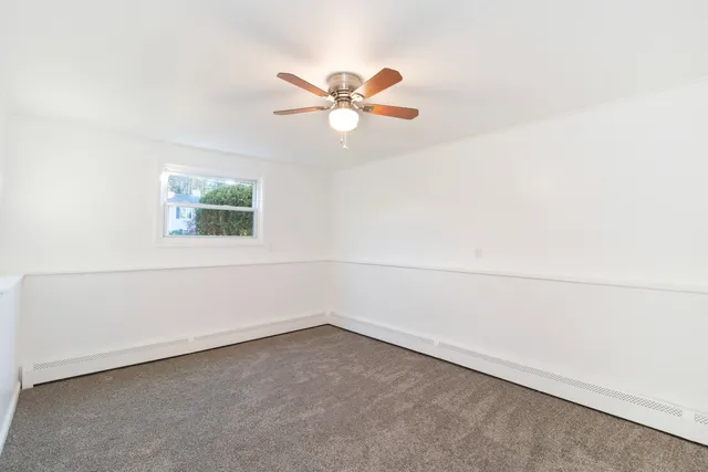 an empty room with a window and a ceiling fan