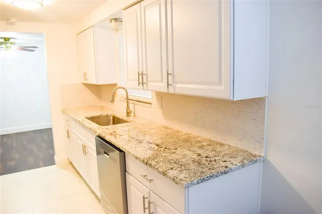 a kitchen with granite countertop white cabinets and white appliances