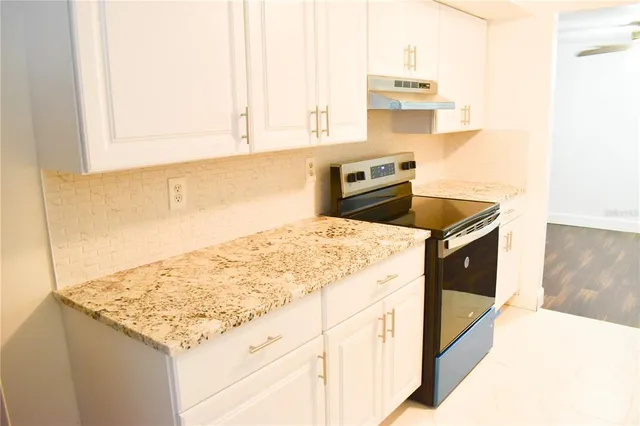 a kitchen with granite countertop a sink stove and refrigerator