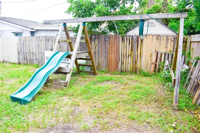 a view of a backyard with a slide and wooden fence