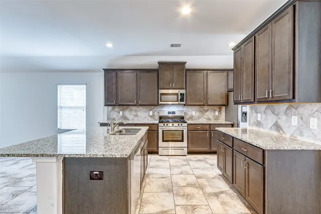 a kitchen with stainless steel appliances granite countertop a stove top oven sink and cabinets
