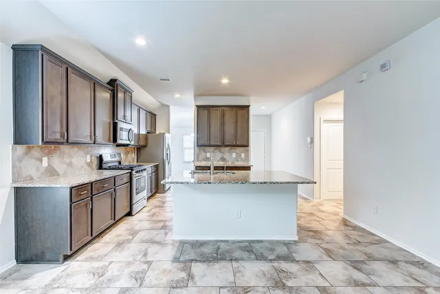 a large kitchen with granite countertop a stove and a sink
