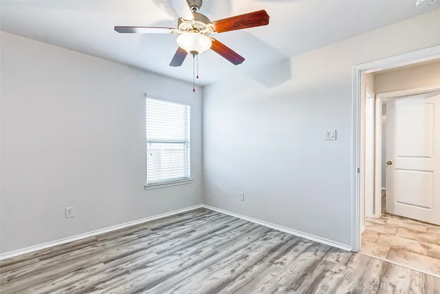 an empty room with a window and a ceiling fan