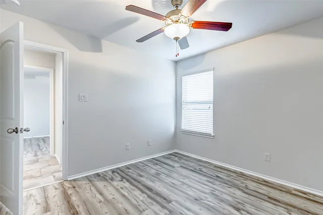 an empty room with a window and a fan