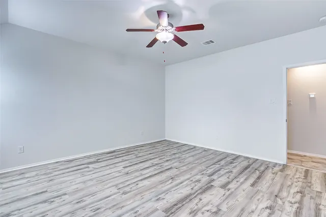 a view of a room with wooden floor a ceiling fan and a chandelier
