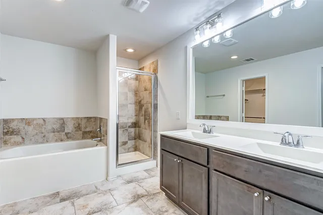 a bathroom with a sink double vanity granite tub shower and a mirror
