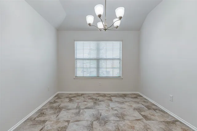 an empty room with a chandelier fan and windows