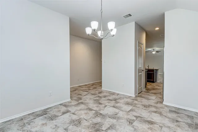 an empty room with kitchen view and hallway