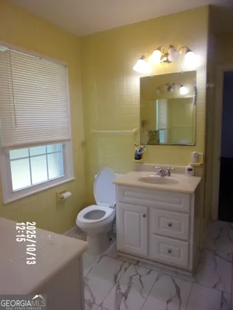 a bathroom with a granite countertop toilet sink and mirror