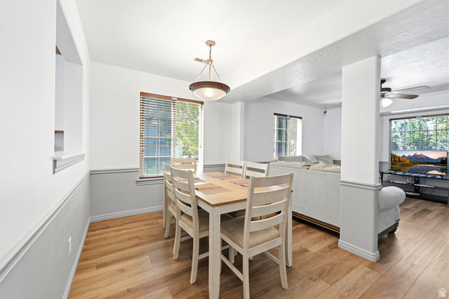 984 Independence Avenue Provo, UT 84604 - Photo 6 of 19 Dining area featuring wood-finish flooring, a contemporary chandelier, a window with horizontal blinds, a pass-through opening to the left, and a half-wall partition