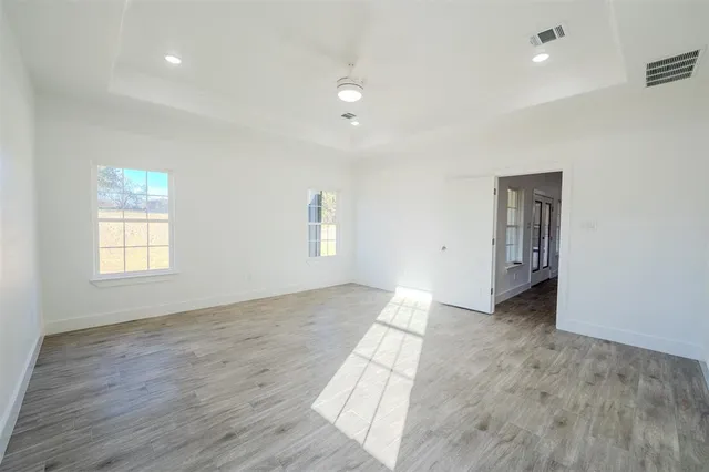 an empty room with wooden floor and windows