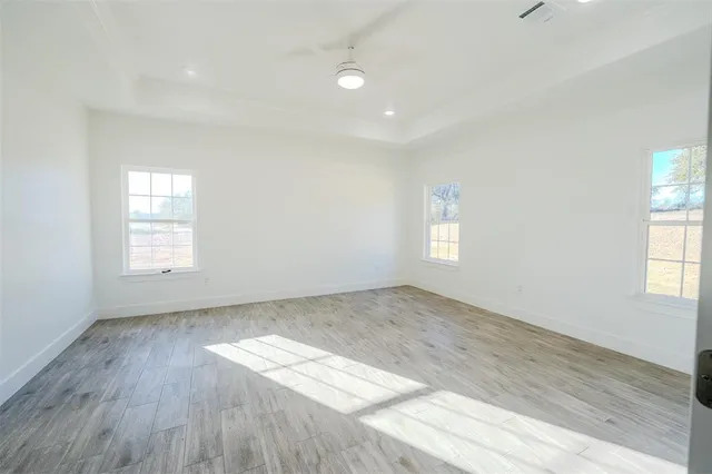 an empty room with wooden floor and windows