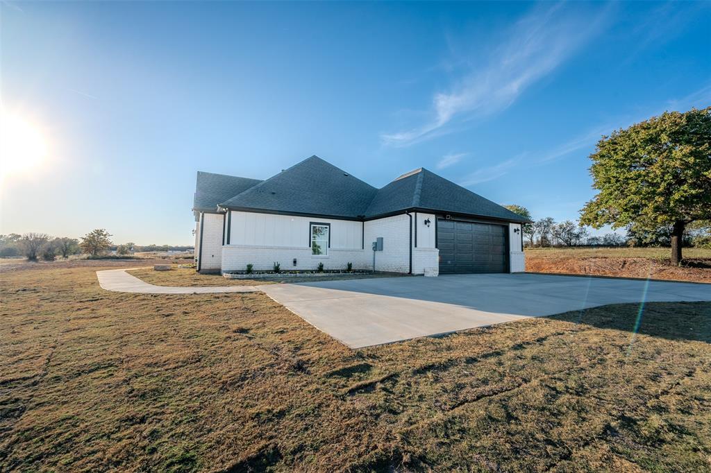 200 Kilkenny Road Poolville, TX 76487 - Photo 26 of 30 View of front facade featuring brick siding, a shingled roof, a front yard, and a garage