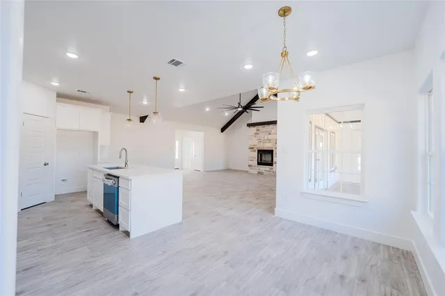 a large kitchen with a large counter top a sink stainless steel appliances and cabinets