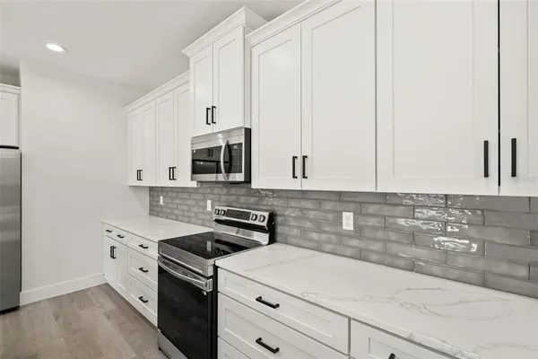a kitchen with stainless steel appliances granite countertop a sink a oven a refrigerator and white cabinets