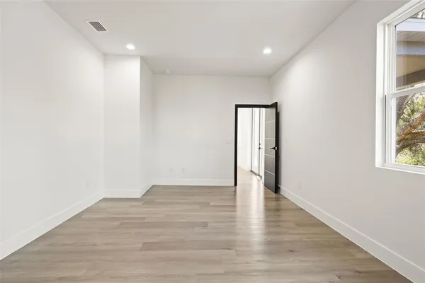 a view of an empty room with wooden floor and a bathroom