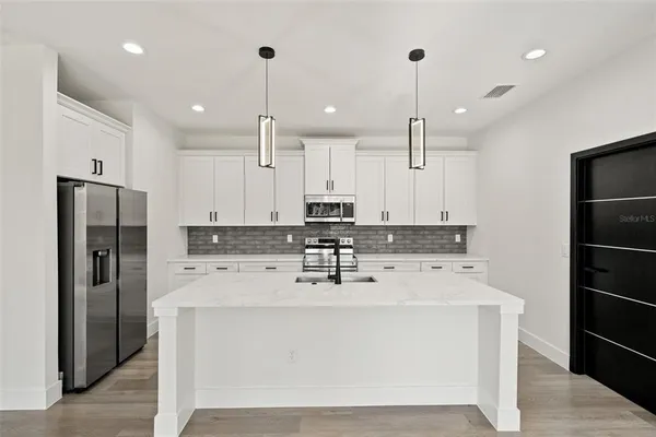 a kitchen with stainless steel appliances a stove refrigerator sink and cabinets