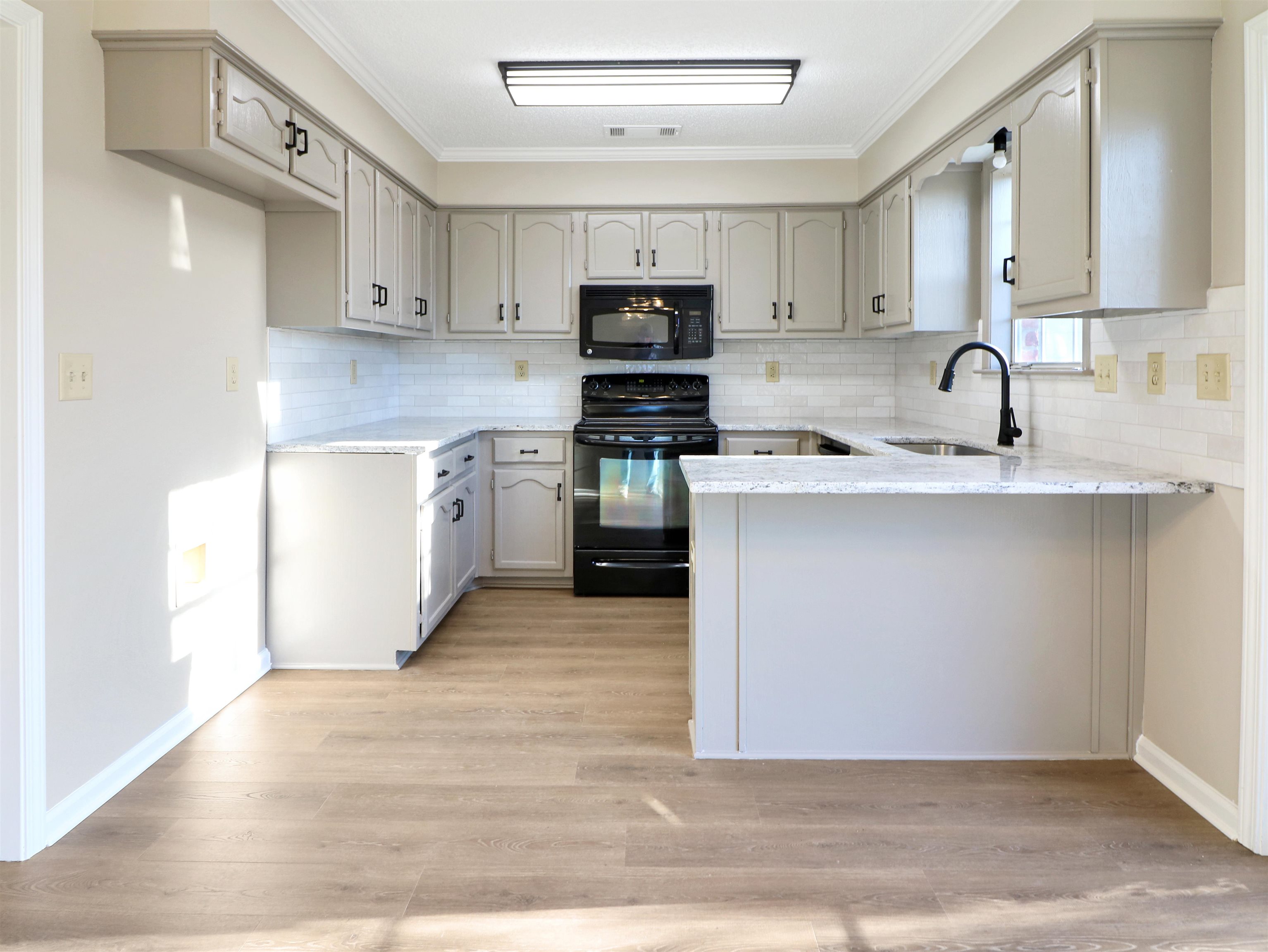 2321 Valley Edge Cove Memphis, TN 38016 - Photo 7 of 18 a kitchen with stainless steel appliances granite countertop a stove top oven a sink and dishwasher with wooden floors