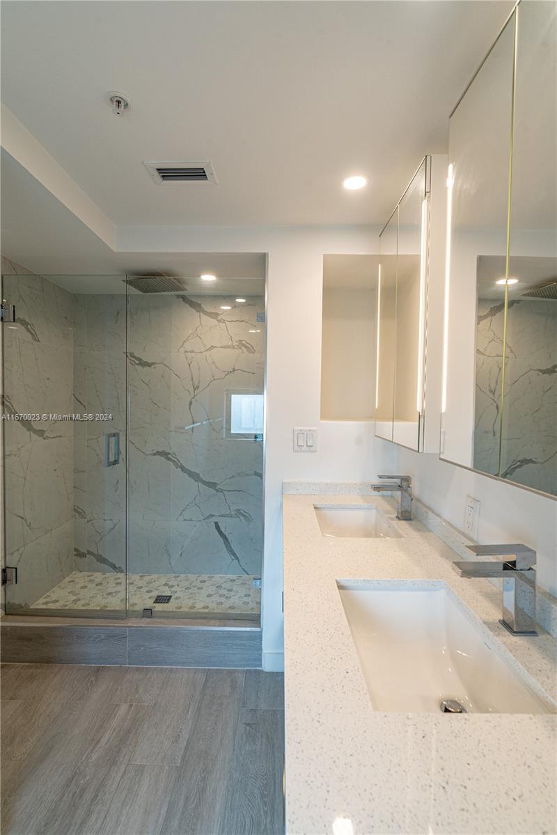 8425 Crespi Boulevard, Unit TH4 Miami Beach, FL 33141 - Photo 23 of 26 a bathroom with a granite countertop sink mirror and shower