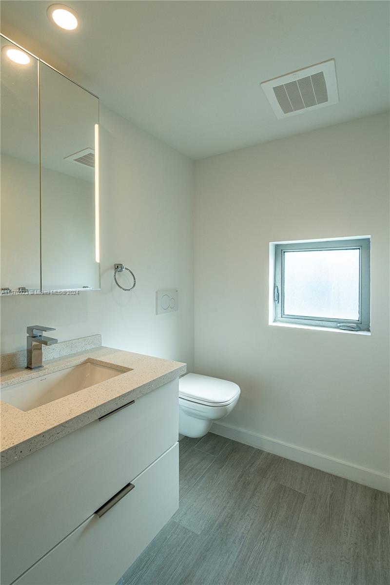 8425 Crespi Boulevard, Unit TH4 Miami Beach, FL 33141 - Photo 24 of 26 a bathroom with a granite countertop sink a toilet and a mirror