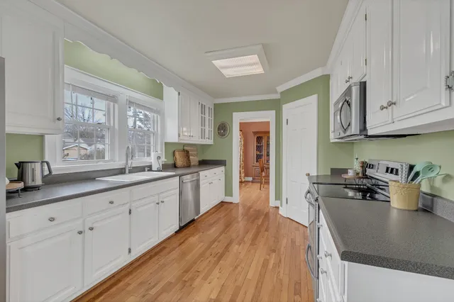 a large kitchen with stainless steel appliances granite countertop a lot of counter space and wooden floors