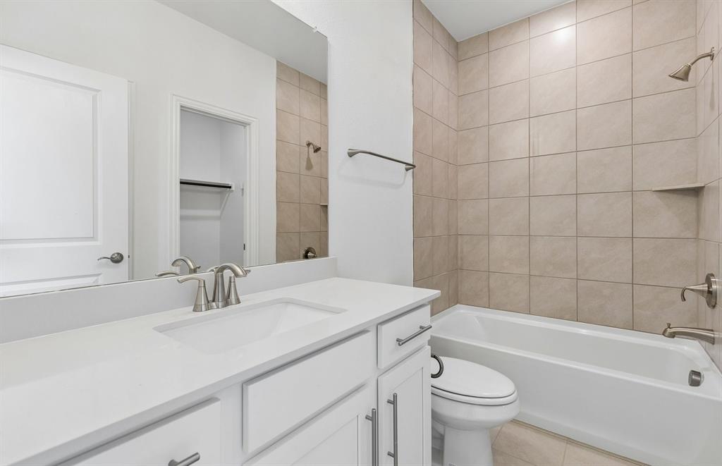 11220 Abbotsbury Road Fort Worth, TX 76052 - Photo 15 of 32 a bathroom with a sink a toilet a mirror a vanity and bathtub