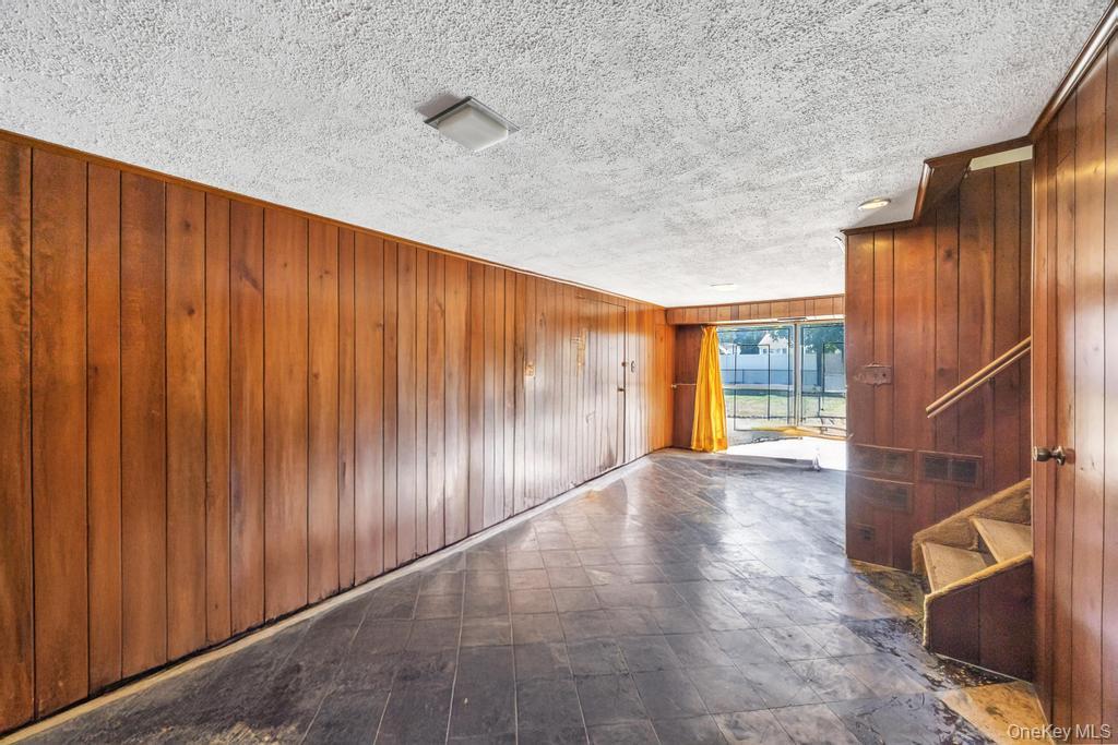 196 Haypath Road Old Bethpage, NY 11804 - Photo 18 of 21 Spare room featuring stairway, wooden walls, and a textured ceiling