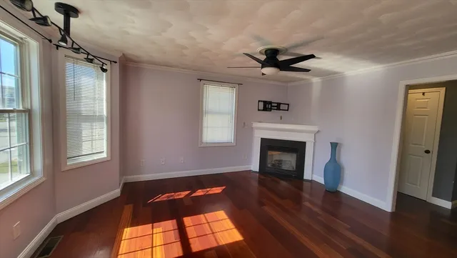 a view of a livingroom with a fireplace wooden floor and windows