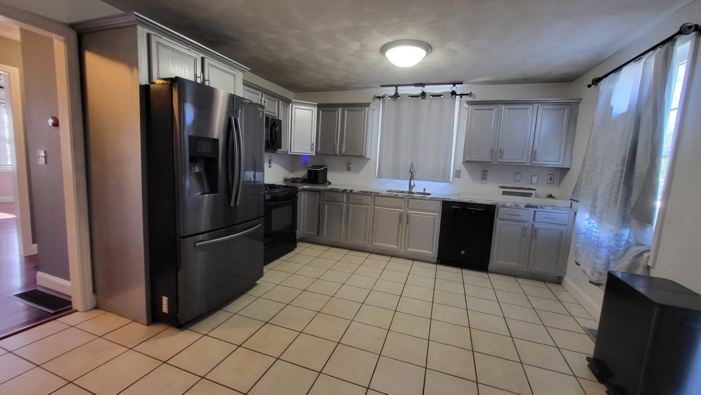 129 Manchester Street, Unit B Lowell, MA 01852 - Photo 4 of 26 a kitchen with stainless steel appliances granite countertop a refrigerator and a sink