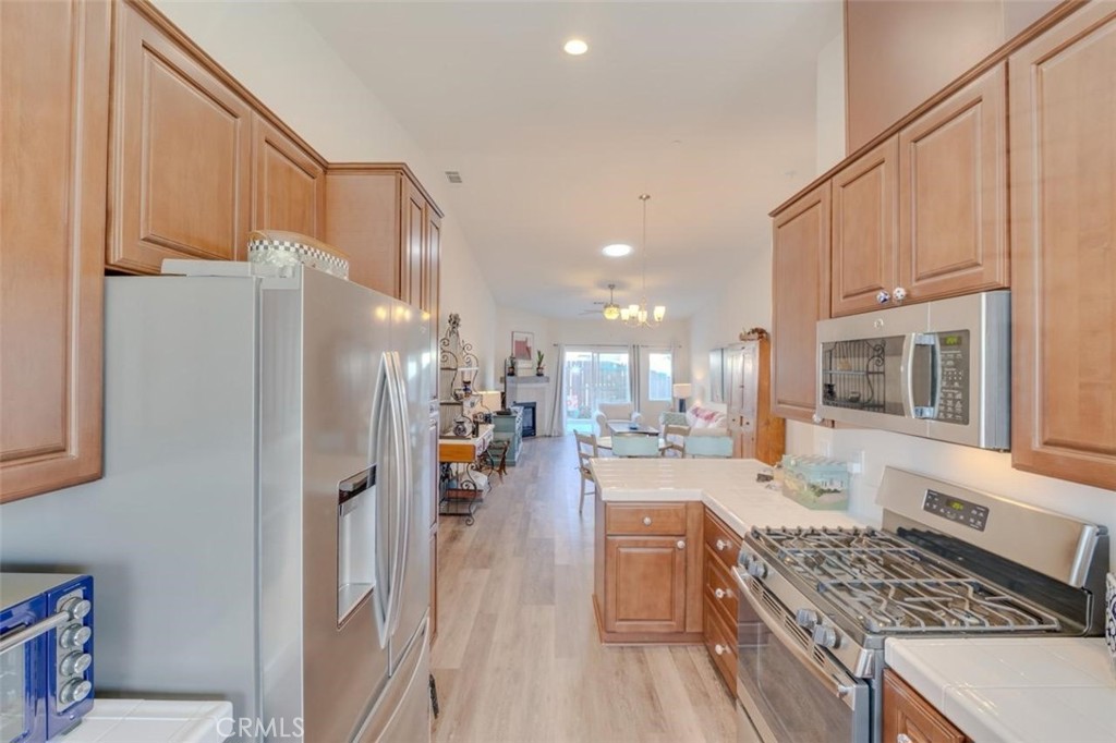 1526 South Fulton Court Santa Maria, CA 93458 - Photo 14 of 39 a kitchen with a refrigerator a stove and white cabinets with wooden floor