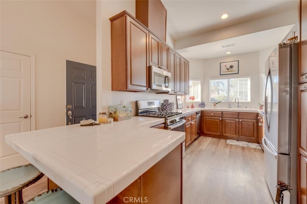 1526 South Fulton Court Santa Maria, CA 93458 - Photo 9 of 39 a kitchen with stainless steel appliances a stove a sink a refrigerator and white cabinets with wooden floor