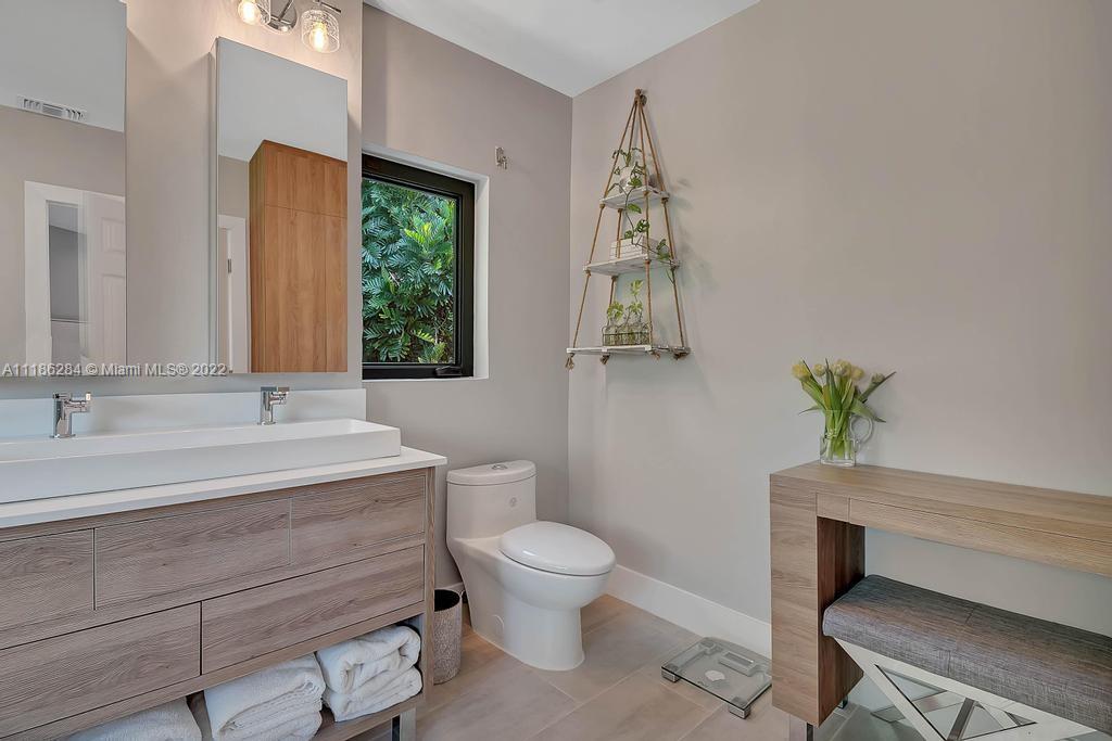 3263 Allamanda Street, Unit 3263 Miami, FL 33133 - Photo 17 of 28 a bathroom with a granite countertop toilet a sink and a window