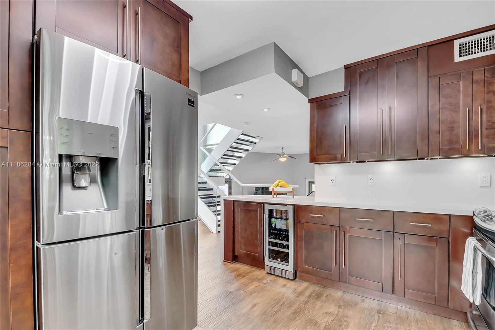 3263 Allamanda Street, Unit 3263 Miami, FL 33133 - Photo 10 of 28 a kitchen with stainless steel appliances a refrigerator and wooden cabinets