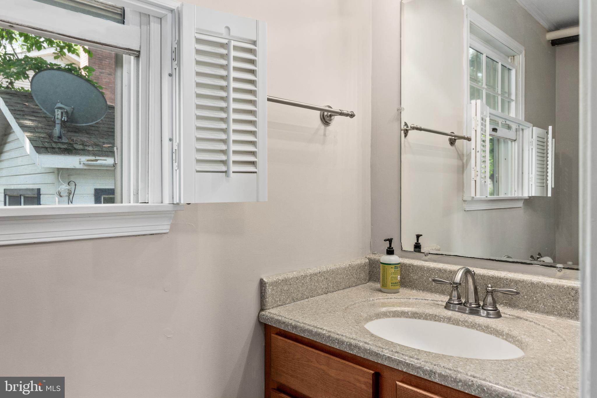 101 Sinclair Street Oxford, MD 21654 - Photo 16 of 31 a bathroom with a granite countertop sink a mirror and a shower