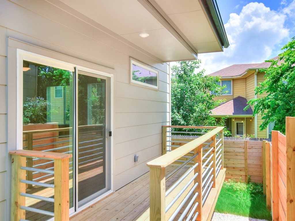 6800 Menchaca Road, Unit 39 Austin, TX 78745 - Photo 2 of 16 Sliding glass doors open directly to a private wood-planked balcony overlooking the yard.