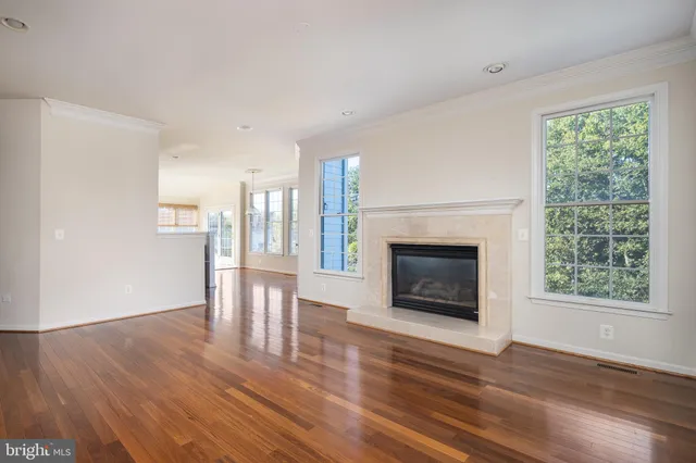 a view of an empty room with wooden floor fireplace and a window