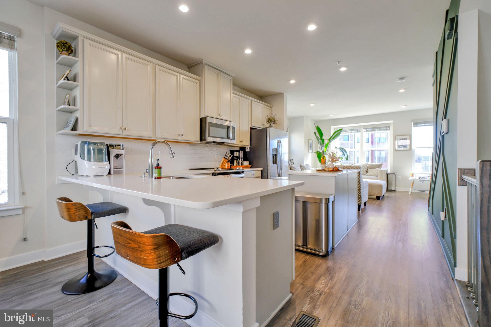 3420 16th Street Northwest, Unit 101 Washington, DC 20010 - Photo 6 of 29 a kitchen with stainless steel appliances kitchen island granite countertop a stove a sink a refrigerator and cabinets