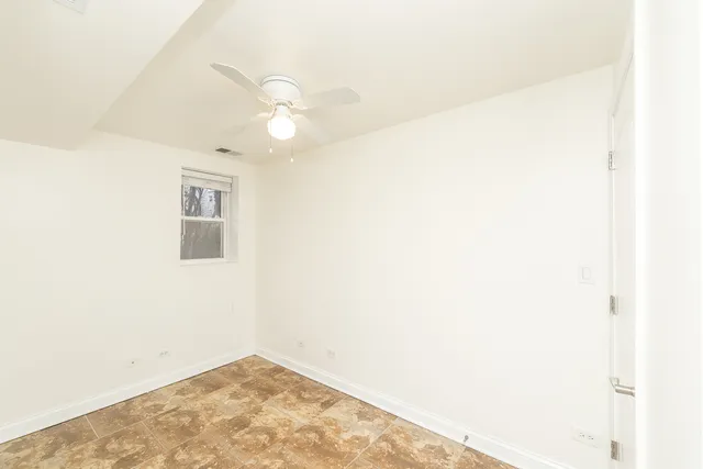 an empty room with a ceiling fan and a window
