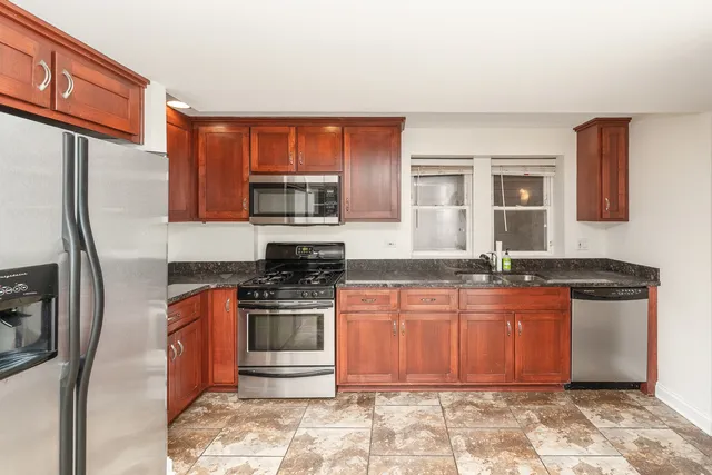 a kitchen with stainless steel appliances granite countertop a stove a sink and a refrigerator