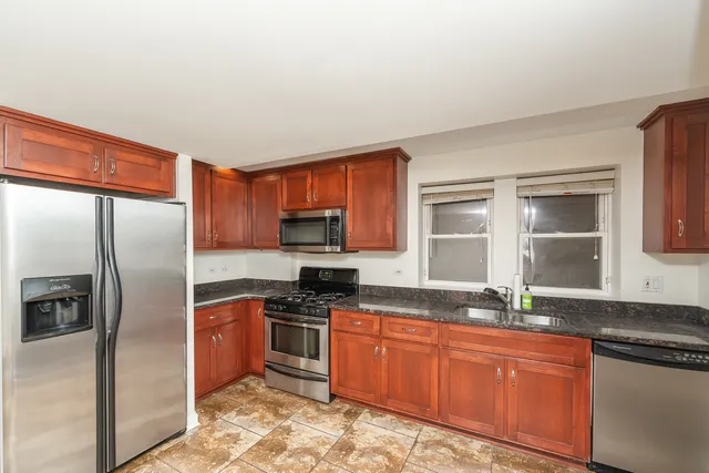 a kitchen with stainless steel appliances granite countertop a sink stove refrigerator and cabinets