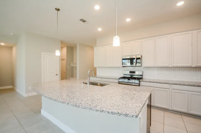 a kitchen with granite countertop a sink a center island stainless steel appliances and cabinets
