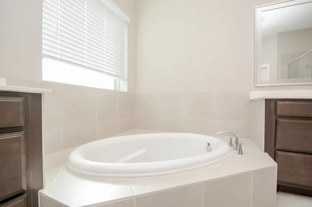a bathroom with a tub sink double vanity granite and toilet
