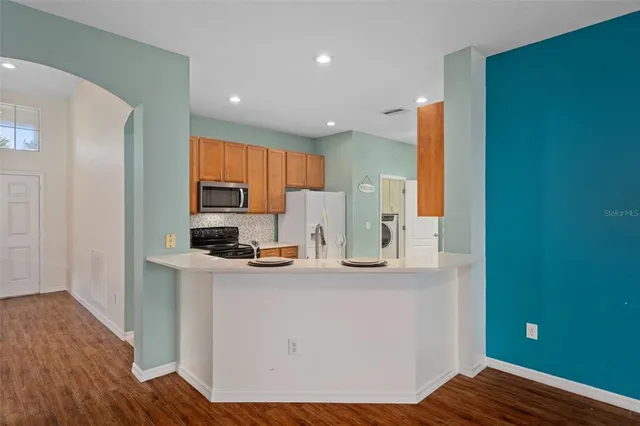 a view of a kitchen with kitchen island a sink wooden floor and living room