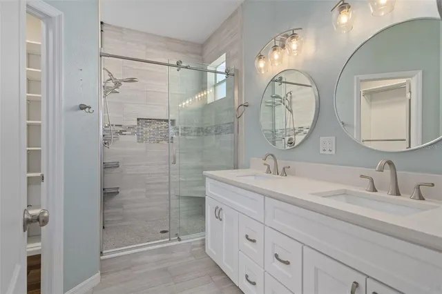 a bathroom with a double vanity sink mirror and shower