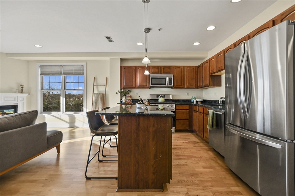 1306 Columbia Road, Unit 3E Boston, MA 02127 - Photo 11 of 40 a kitchen with stainless steel appliances granite countertop a refrigerator a stove a sink a dining table and chairs with wooden floor