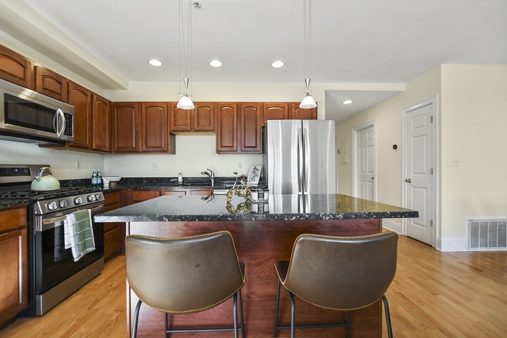 1306 Columbia Road, Unit 3E Boston, MA 02127 - Photo 13 of 40 a kitchen with stainless steel appliances granite countertop a stove a sink a microwave a refrigerator and chairs