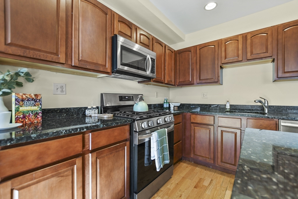 1306 Columbia Road, Unit 3E Boston, MA 02127 - Photo 14 of 40 a kitchen with stainless steel appliances granite countertop a sink stove microwave and cabinets