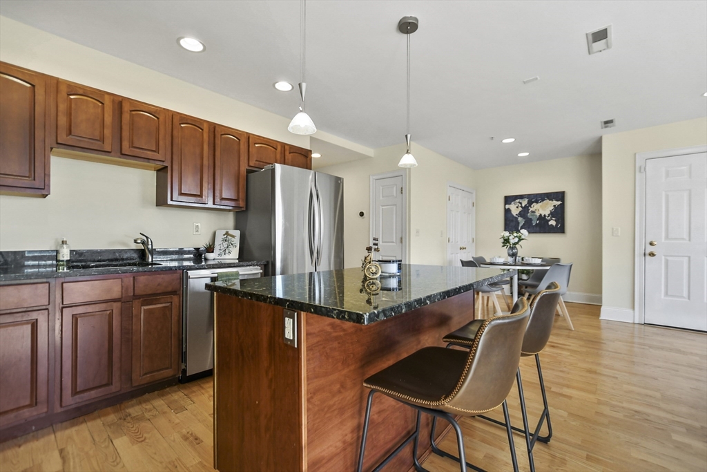 1306 Columbia Road, Unit 3E Boston, MA 02127 - Photo 9 of 40 a kitchen with stainless steel appliances granite countertop a refrigerator a sink dishwasher a dining table and chairs with wooden floor