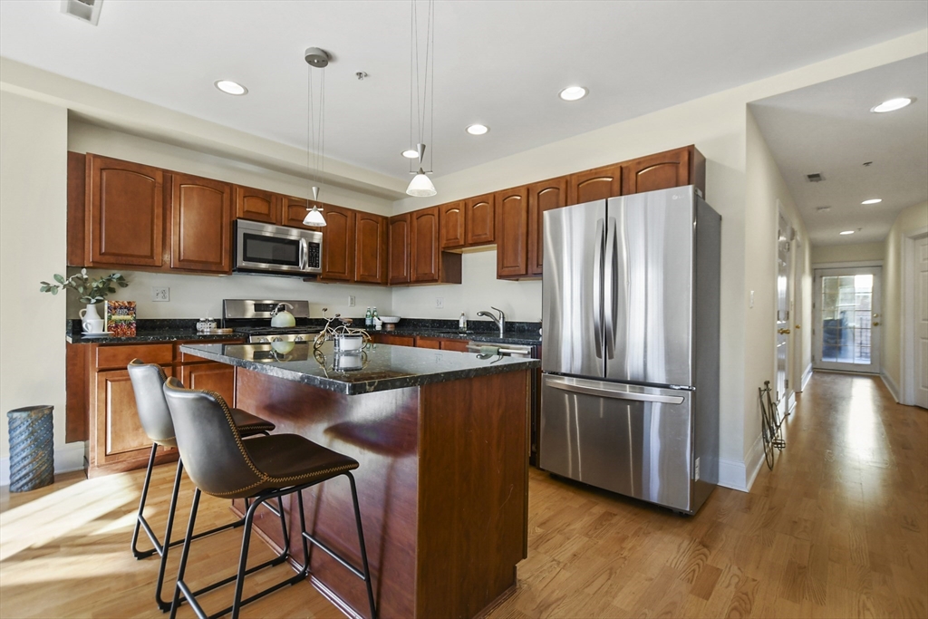 1306 Columbia Road, Unit 3E Boston, MA 02127 - Photo 10 of 40 a kitchen with stainless steel appliances granite countertop a refrigerator a stove top oven a sink and dishwasher